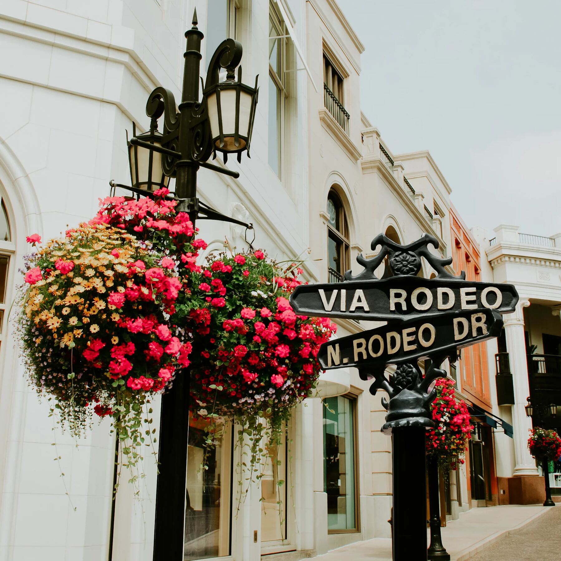 Via Rodeo street sign amid flowering planters in Beverly Hills